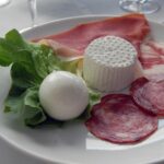 Un piatto tipico emiliano con tortellini, prosciutto e parmigiano, simbolo della strada dei sapori tra Parma e Modena.