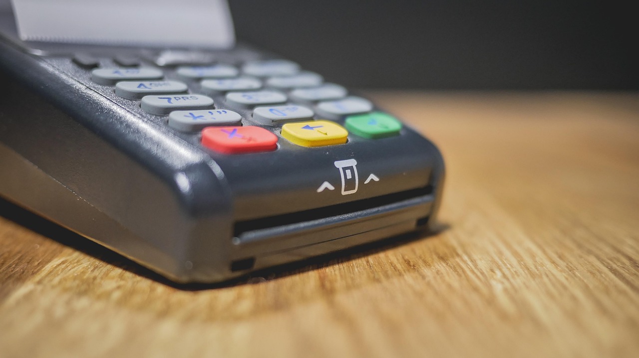 Commerciante che utilizza un POS per transazioni, con focus sulle nuove regole di pagamento.